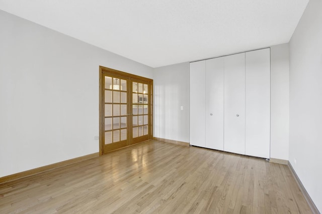 unfurnished bedroom with light hardwood / wood-style floors, a closet, and french doors