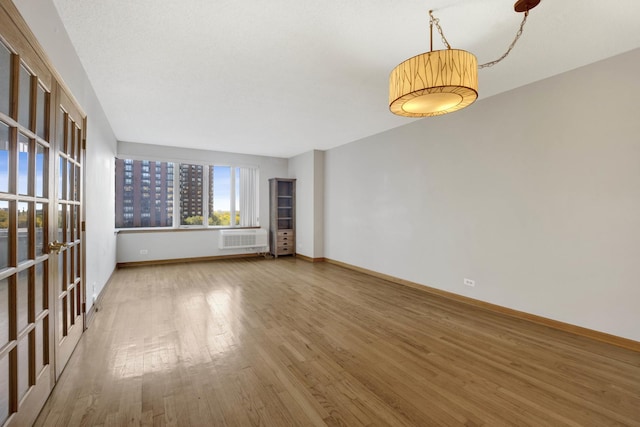 unfurnished living room featuring a wall mounted AC and wood-type flooring