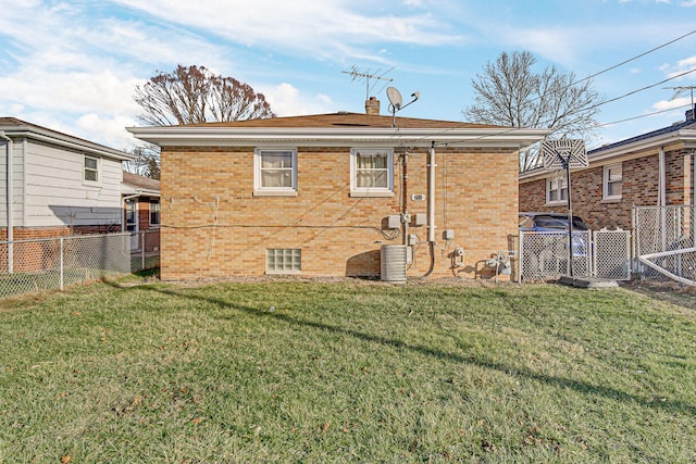 rear view of house with central air condition unit and a yard