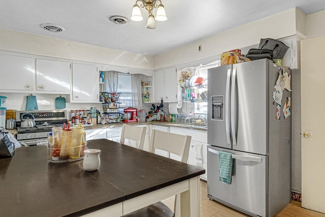 kitchen featuring white cabinets, appliances with stainless steel finishes, sink, and a chandelier