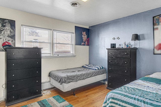 bedroom featuring a baseboard heating unit and hardwood / wood-style floors