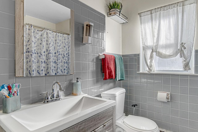 bathroom with toilet, tile walls, tasteful backsplash, and vanity