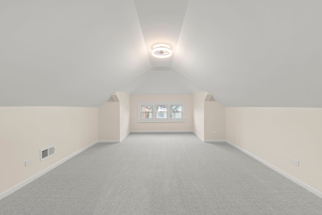 additional living space with light carpet and vaulted ceiling