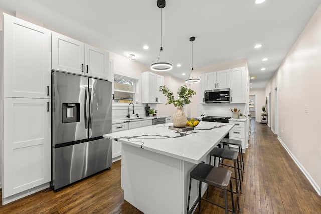 kitchen featuring tasteful backsplash, a kitchen island, white cabinetry, hanging light fixtures, and stainless steel appliances