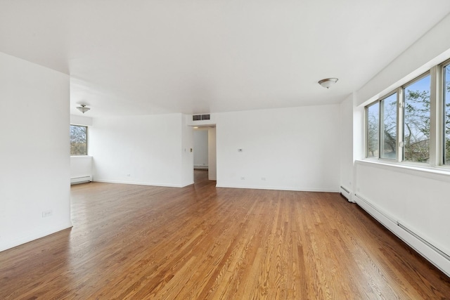 spare room featuring a baseboard heating unit and light hardwood / wood-style floors