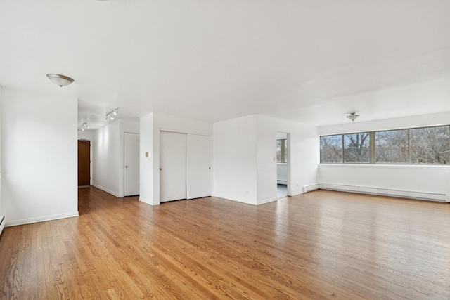 unfurnished living room with light hardwood / wood-style floors and baseboard heating