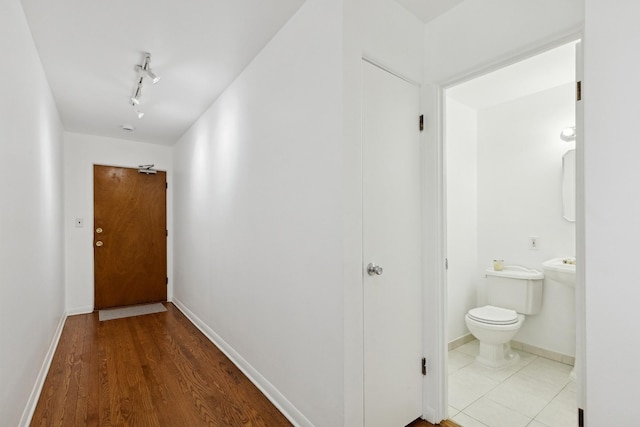 hall with hardwood / wood-style flooring and track lighting