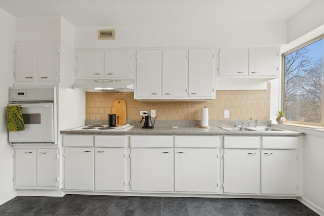 kitchen featuring backsplash, white cabinets, and white appliances