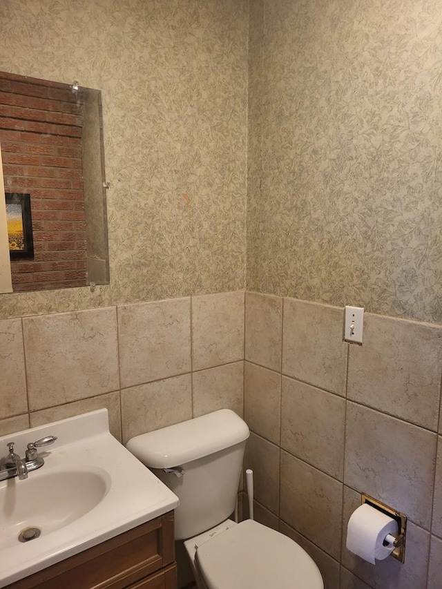 bathroom with vanity, tile walls, and toilet