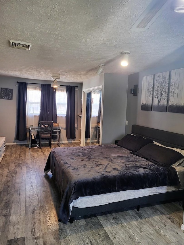 bedroom with ceiling fan, hardwood / wood-style flooring, and a textured ceiling