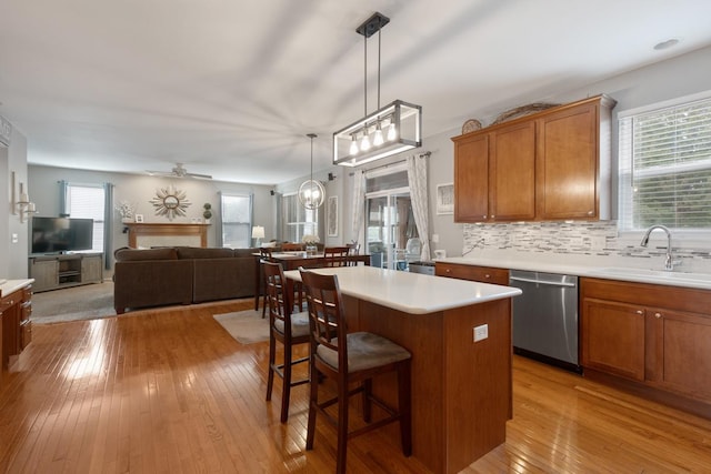 kitchen with a kitchen island, tasteful backsplash, dishwasher, sink, and light hardwood / wood-style floors