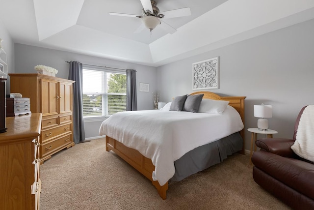 carpeted bedroom featuring a raised ceiling and ceiling fan