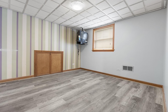 unfurnished room with a drop ceiling and light wood-type flooring