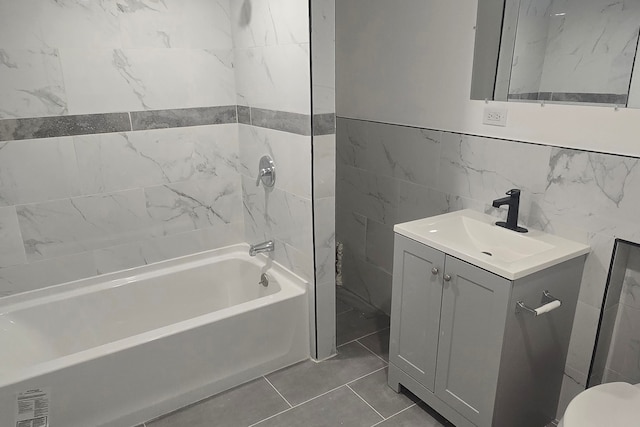 full bathroom with tile patterned floors, vanity, tile walls, toilet, and  shower combination