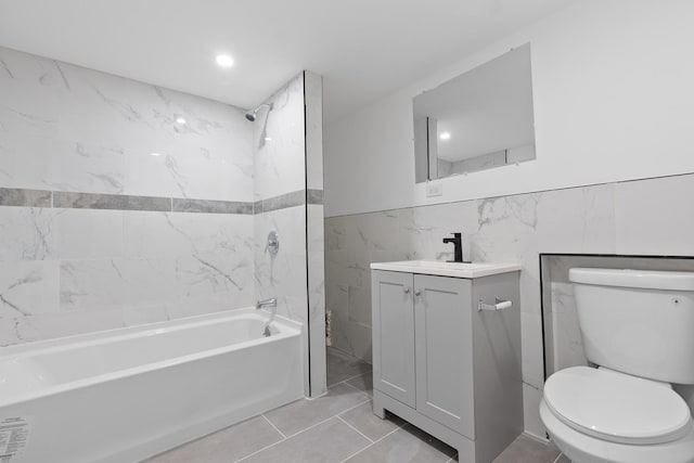 full bathroom featuring tiled shower / bath, vanity, toilet, and tile walls