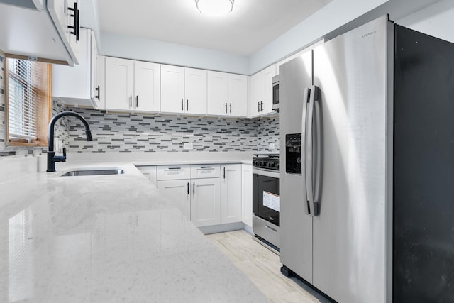 kitchen featuring sink, light stone counters, white cabinets, and appliances with stainless steel finishes