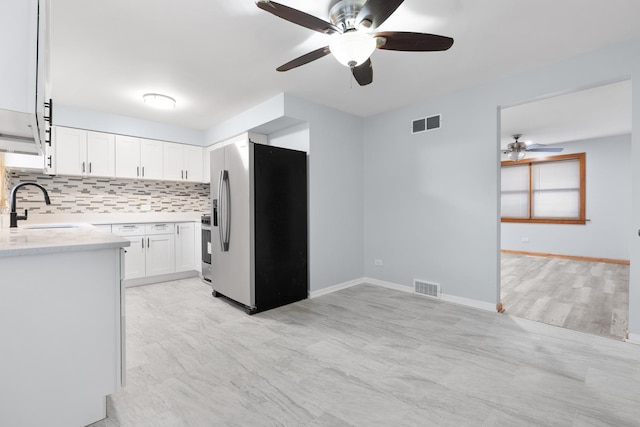 kitchen featuring tasteful backsplash, sink, white cabinets, light stone counters, and stainless steel refrigerator with ice dispenser