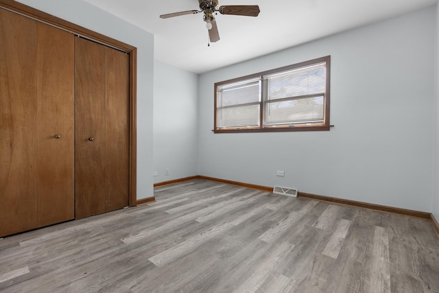 unfurnished bedroom featuring ceiling fan, light hardwood / wood-style floors, and a closet