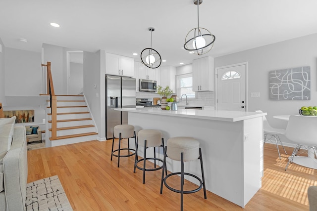 kitchen featuring appliances with stainless steel finishes, decorative backsplash, white cabinetry, and decorative light fixtures