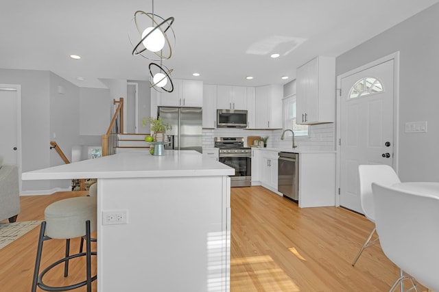 kitchen with white cabinets, pendant lighting, appliances with stainless steel finishes, and a kitchen breakfast bar