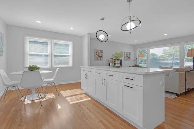 kitchen with light hardwood / wood-style flooring, white cabinets, hanging light fixtures, and a center island