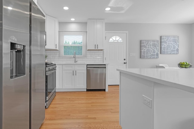 kitchen featuring stainless steel appliances, decorative backsplash, white cabinetry, and sink