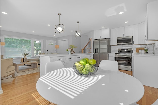 kitchen featuring decorative light fixtures, tasteful backsplash, a kitchen island, stainless steel appliances, and white cabinets