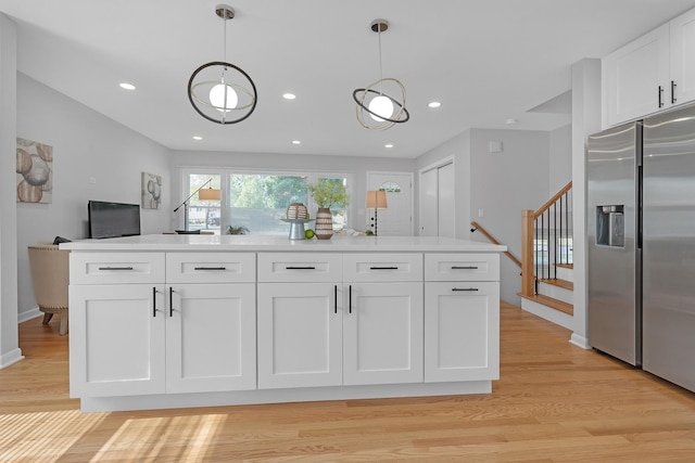 kitchen with a center island, light hardwood / wood-style floors, stainless steel refrigerator with ice dispenser, hanging light fixtures, and white cabinets