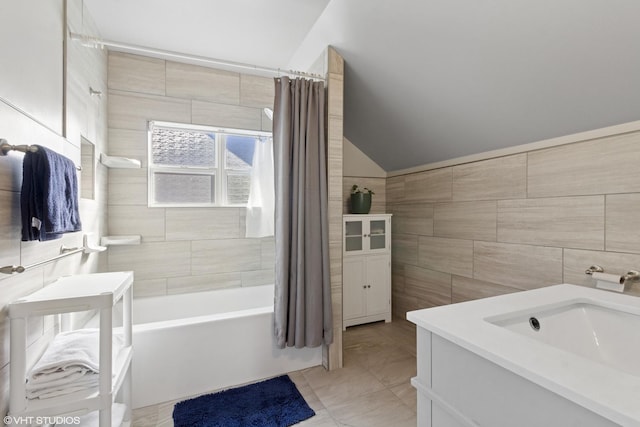 bathroom with tile patterned flooring, shower / tub combo, vanity, tile walls, and vaulted ceiling