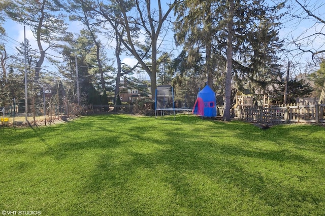 view of yard featuring a trampoline and fence