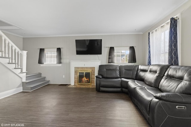 living area with baseboards, a tile fireplace, wood finished floors, stairs, and crown molding