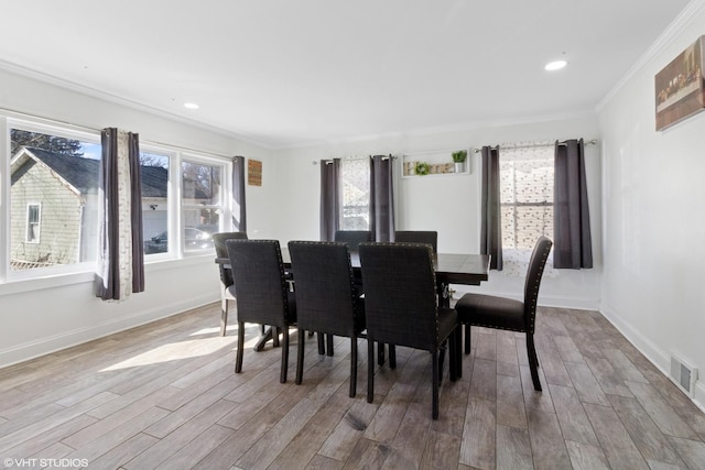 dining room featuring ornamental molding, wood finished floors, visible vents, and baseboards