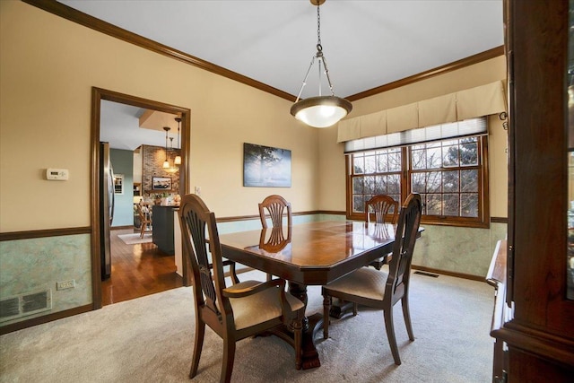 carpeted dining room with ornamental molding