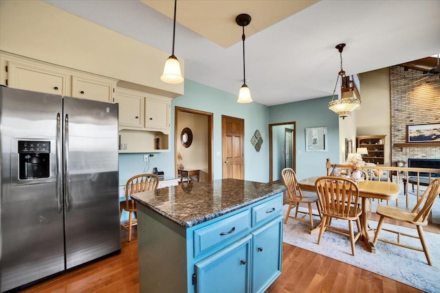 kitchen with stainless steel refrigerator with ice dispenser, dark hardwood / wood-style flooring, blue cabinets, a kitchen island, and pendant lighting