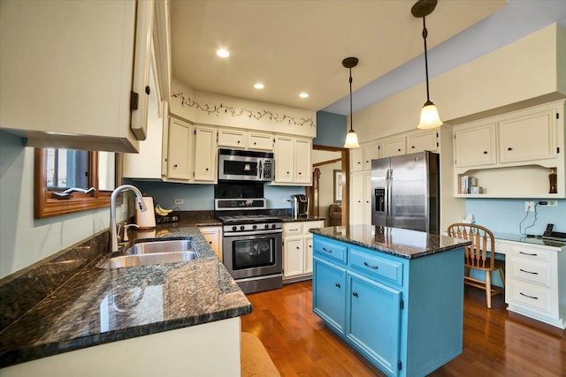 kitchen featuring a center island, sink, hanging light fixtures, stainless steel appliances, and blue cabinets