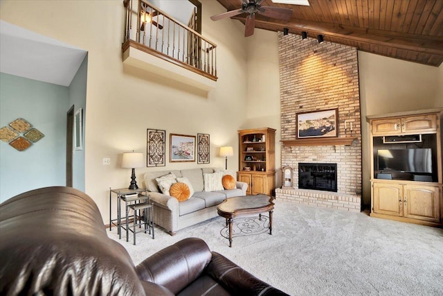 carpeted living room featuring ceiling fan, a fireplace, beamed ceiling, wood ceiling, and high vaulted ceiling