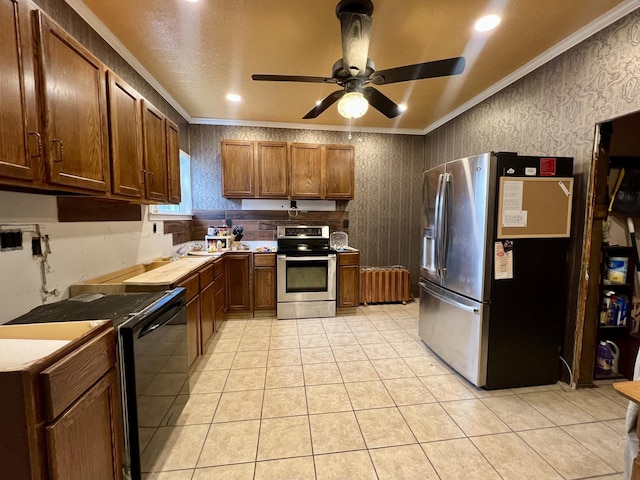 kitchen with light tile patterned flooring, ornamental molding, ceiling fan, and appliances with stainless steel finishes