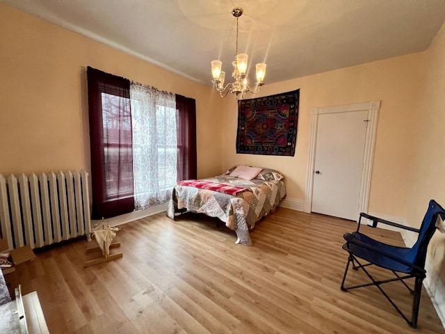 bedroom featuring radiator, hardwood / wood-style floors, and a notable chandelier