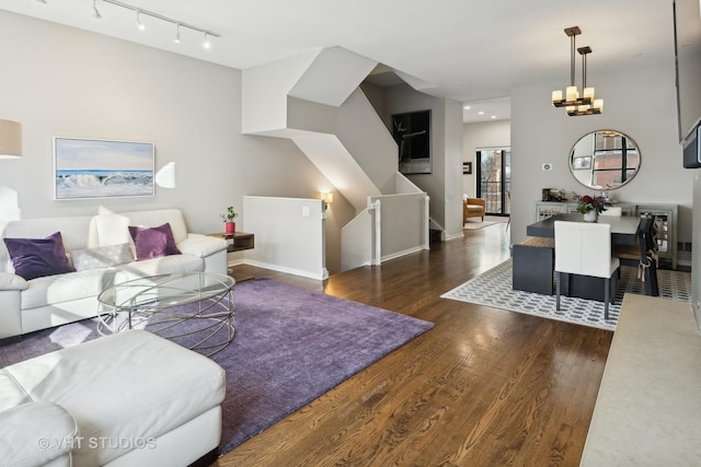 living room with an inviting chandelier, dark hardwood / wood-style flooring, and rail lighting