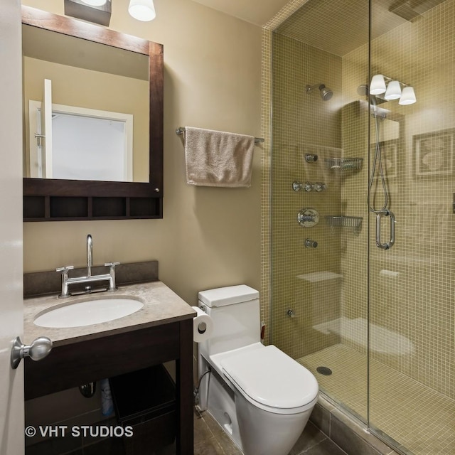 bathroom featuring toilet, a shower with shower door, and sink