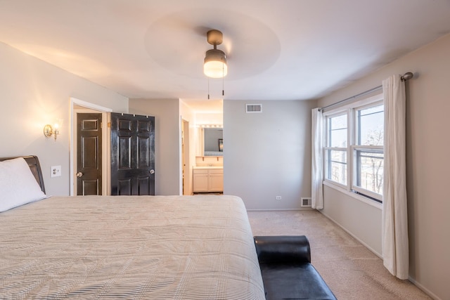 bedroom featuring light carpet, ensuite bath, and ceiling fan