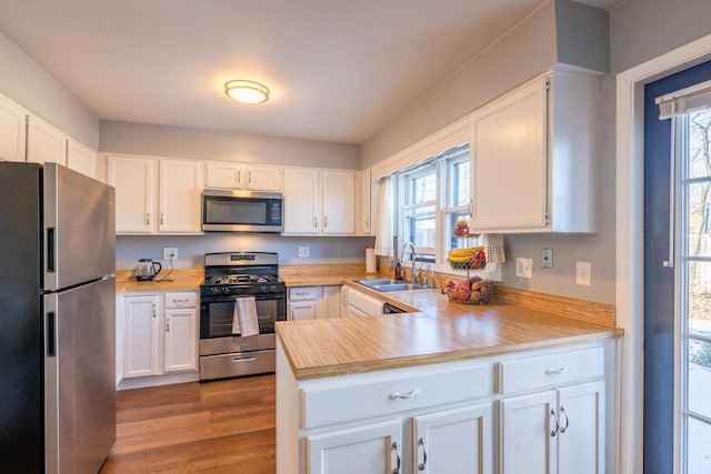 kitchen featuring sink, light hardwood / wood-style flooring, white cabinets, and appliances with stainless steel finishes