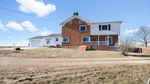 rear view of house featuring central AC unit, a garage, and a porch