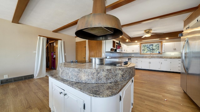 kitchen with dark stone countertops, sink, stainless steel refrigerator, and white cabinets