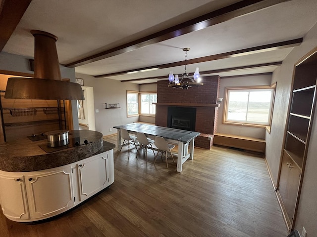 kitchen with pendant lighting, hardwood / wood-style flooring, white cabinetry, a fireplace, and beamed ceiling