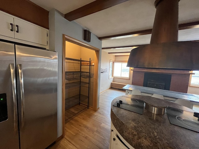 kitchen featuring beamed ceiling, white cabinets, light hardwood / wood-style floors, and stainless steel fridge with ice dispenser