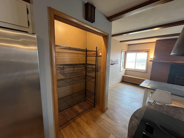 bathroom with a fireplace, beam ceiling, and wood-type flooring