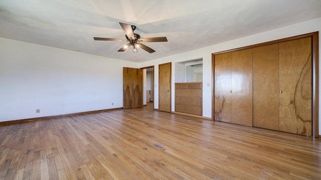 unfurnished bedroom with two closets, ceiling fan, and light wood-type flooring