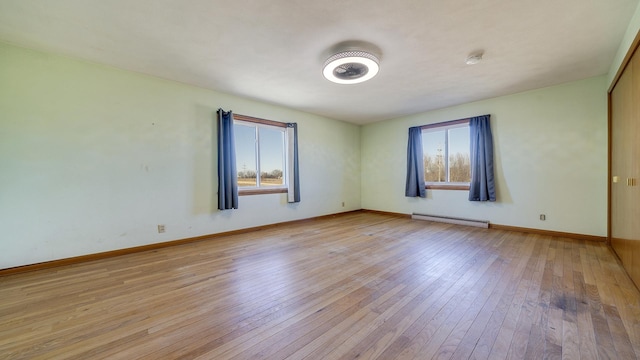 spare room with baseboard heating and light wood-type flooring