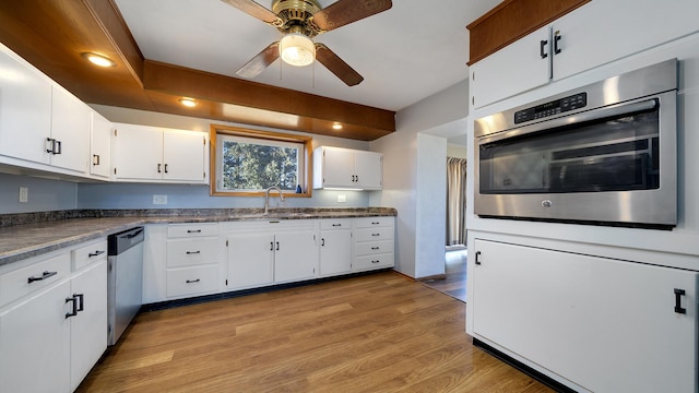 kitchen with appliances with stainless steel finishes, white cabinetry, light wood-type flooring, and sink